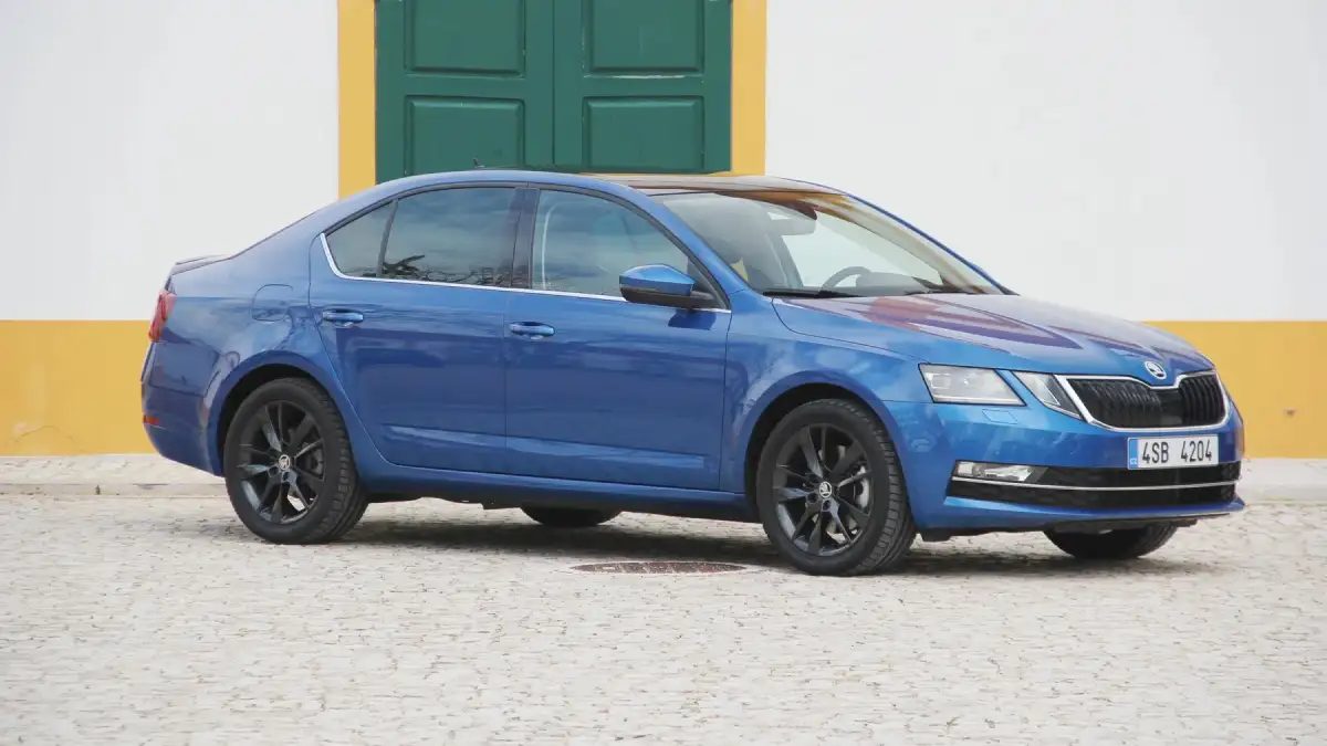 Синя Škoda Octavia III лифтбек, паркирана пред сграда със зелена врата